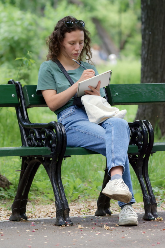 Girl sitting on a bench and writing